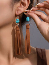 Close-up of a person wearing tassel earrings with turquoise stones.
