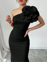 Black one-shoulder dress with a large floral embellishment on a plain background