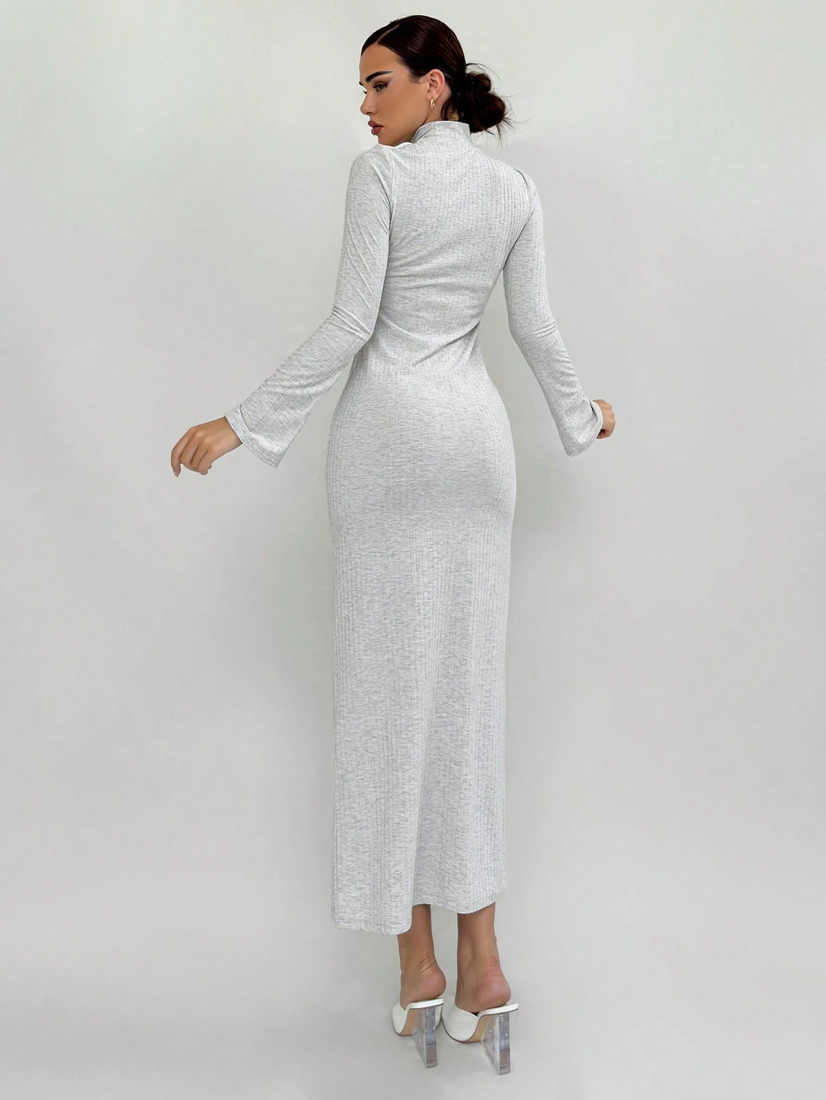Woman wearing a long, light gray dress against a white background