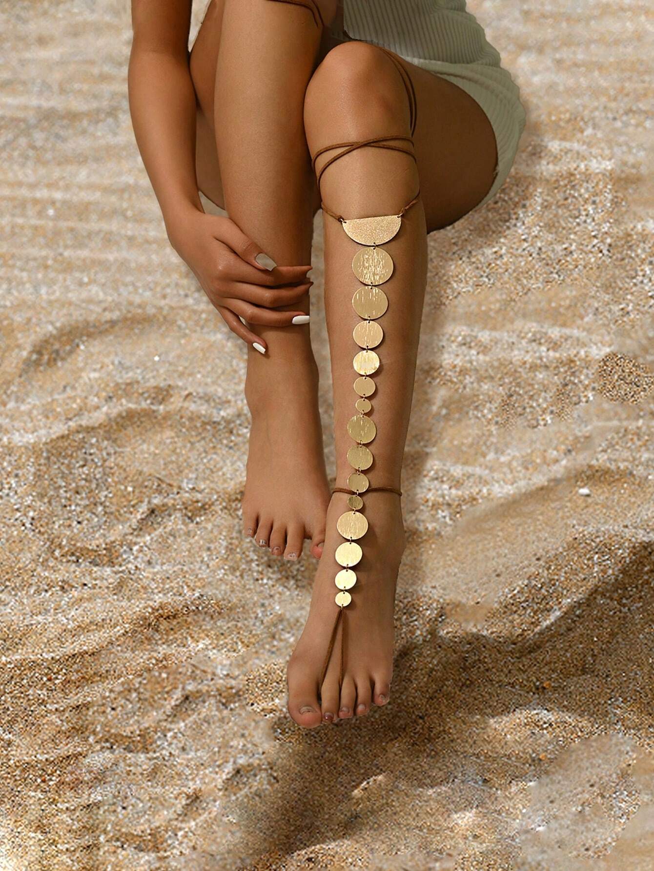 Person wearing gold anklets on a textured stone surface