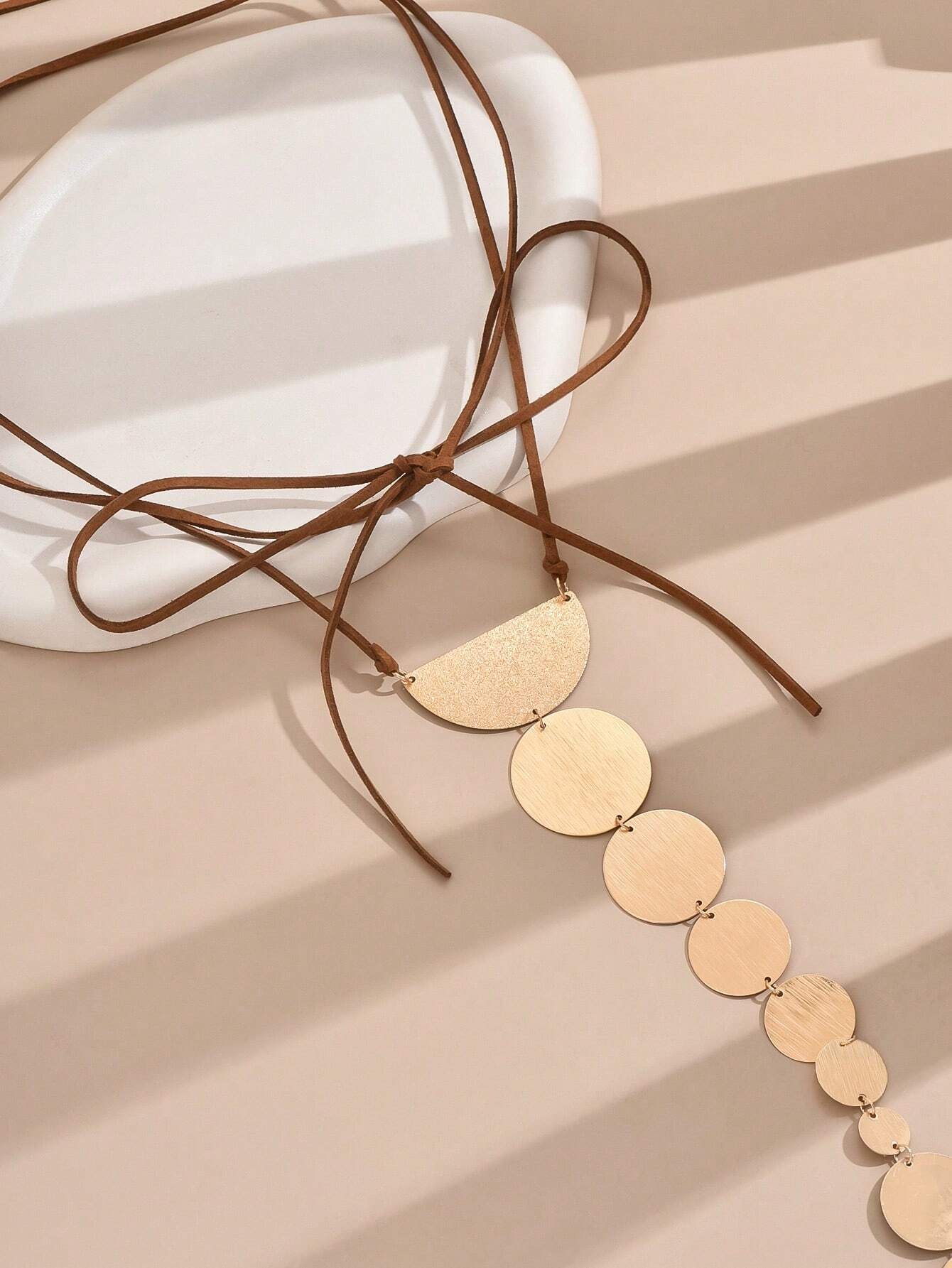 Gold necklace with circular pendants on a beige surface