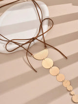 Gold necklace with circular pendants on a beige surface