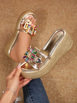 Gold platform sandal with colorful embellishments on a brown background