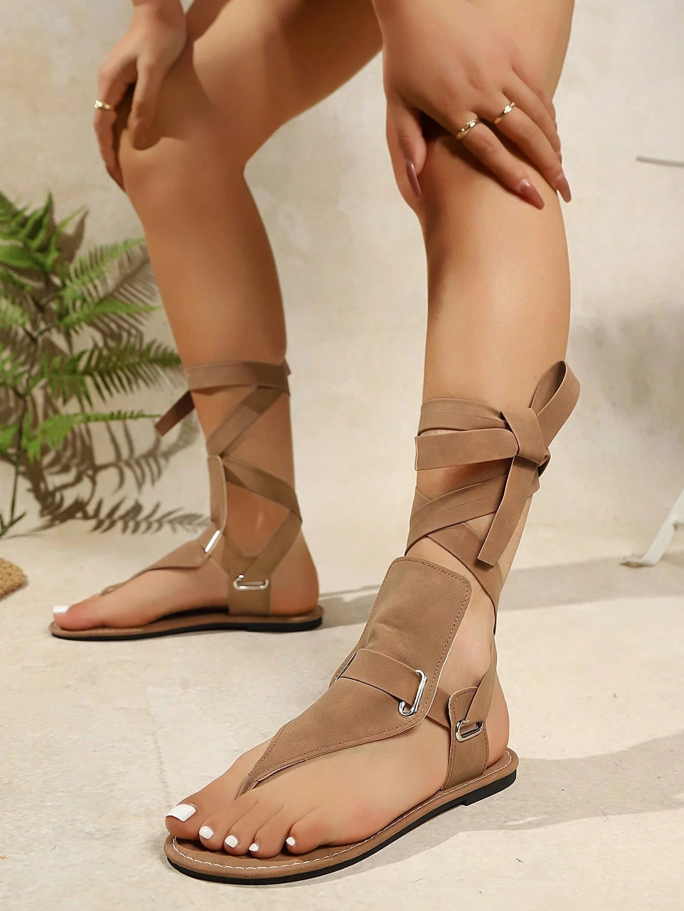 Beige gladiator sandals worn by a person on a light background