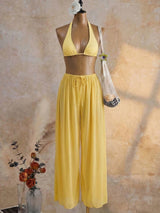 Yellow bikini set on a mannequin against a textured beige wall.