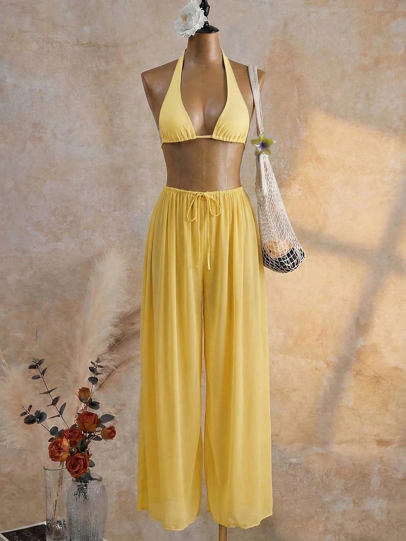 Yellow bikini set on a mannequin against a textured beige wall.