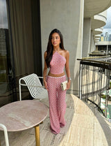 Woman in a pink patterned outfit standing on a balcony with cityscape view