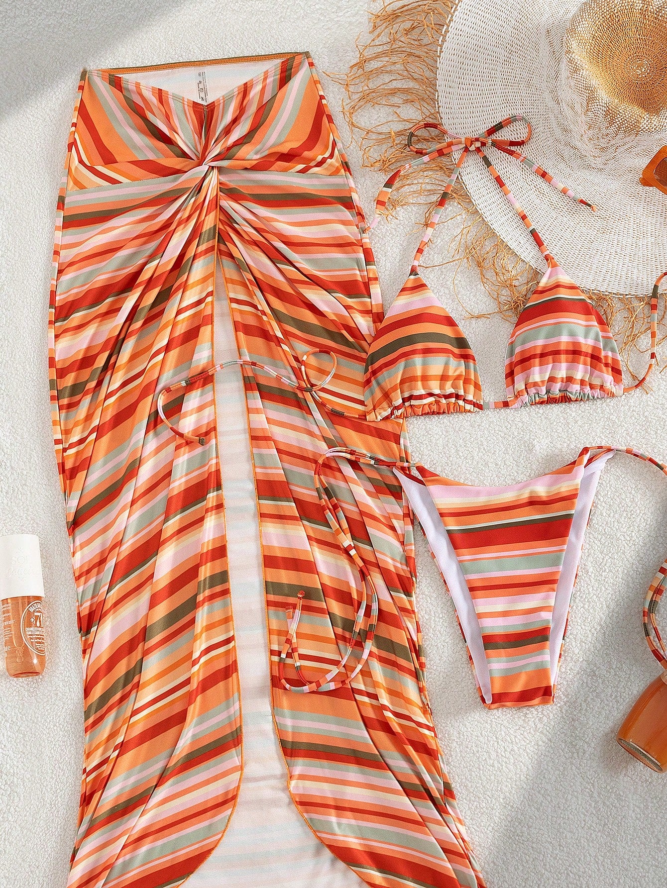 Striped swimsuit set with a sun hat and beach accessories on sand