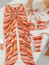 Striped swimsuit set with a sun hat and beach accessories on sand