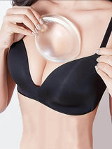 Person wearing a black bra with a silicone gel pad on a plain background