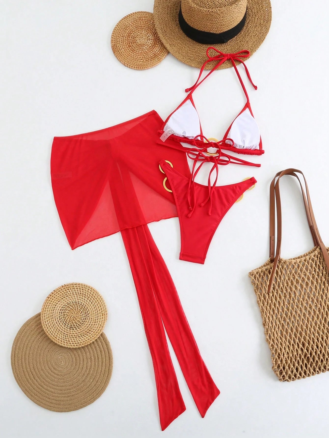 Red bikini set with white top, straw hat, and bag on a white background