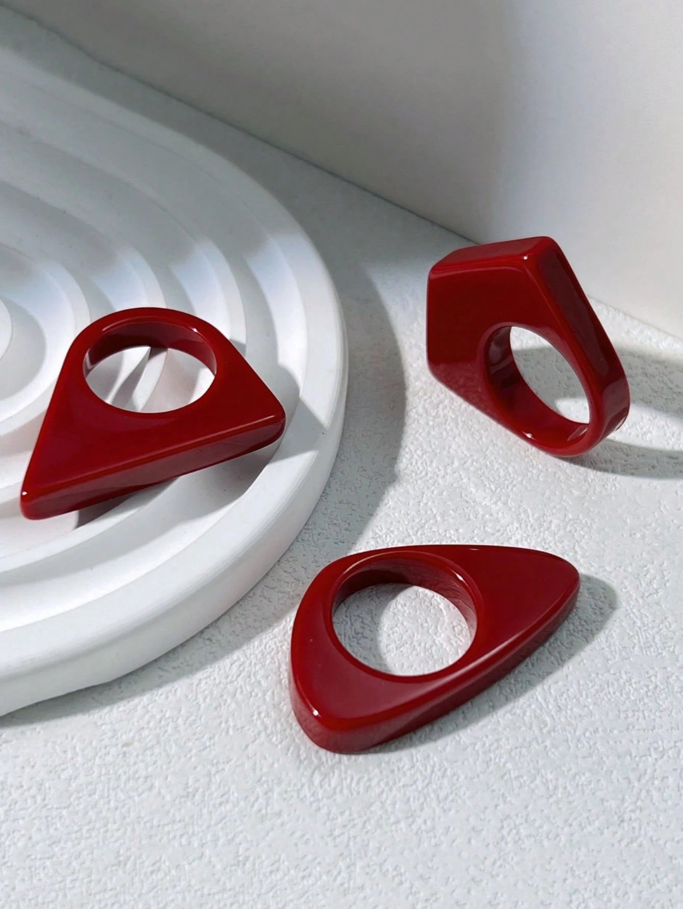 Three red geometric rings on a textured white surface