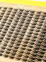 Close-up of a tray of false eyelash clusters on a beige card with the brand name KISHIYO printed repeatedly at the top.