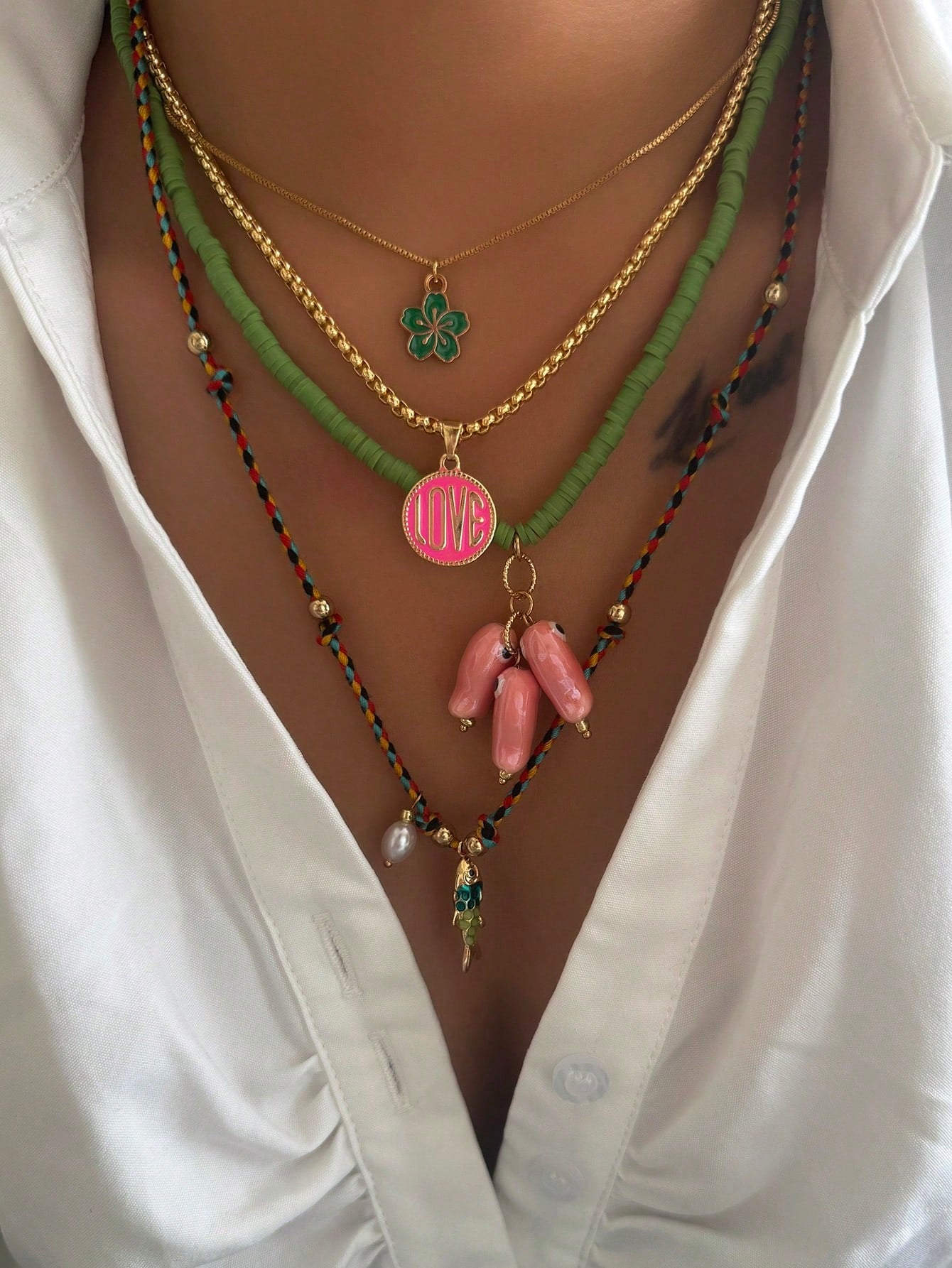 Necklace with various pendants on a white shirt background