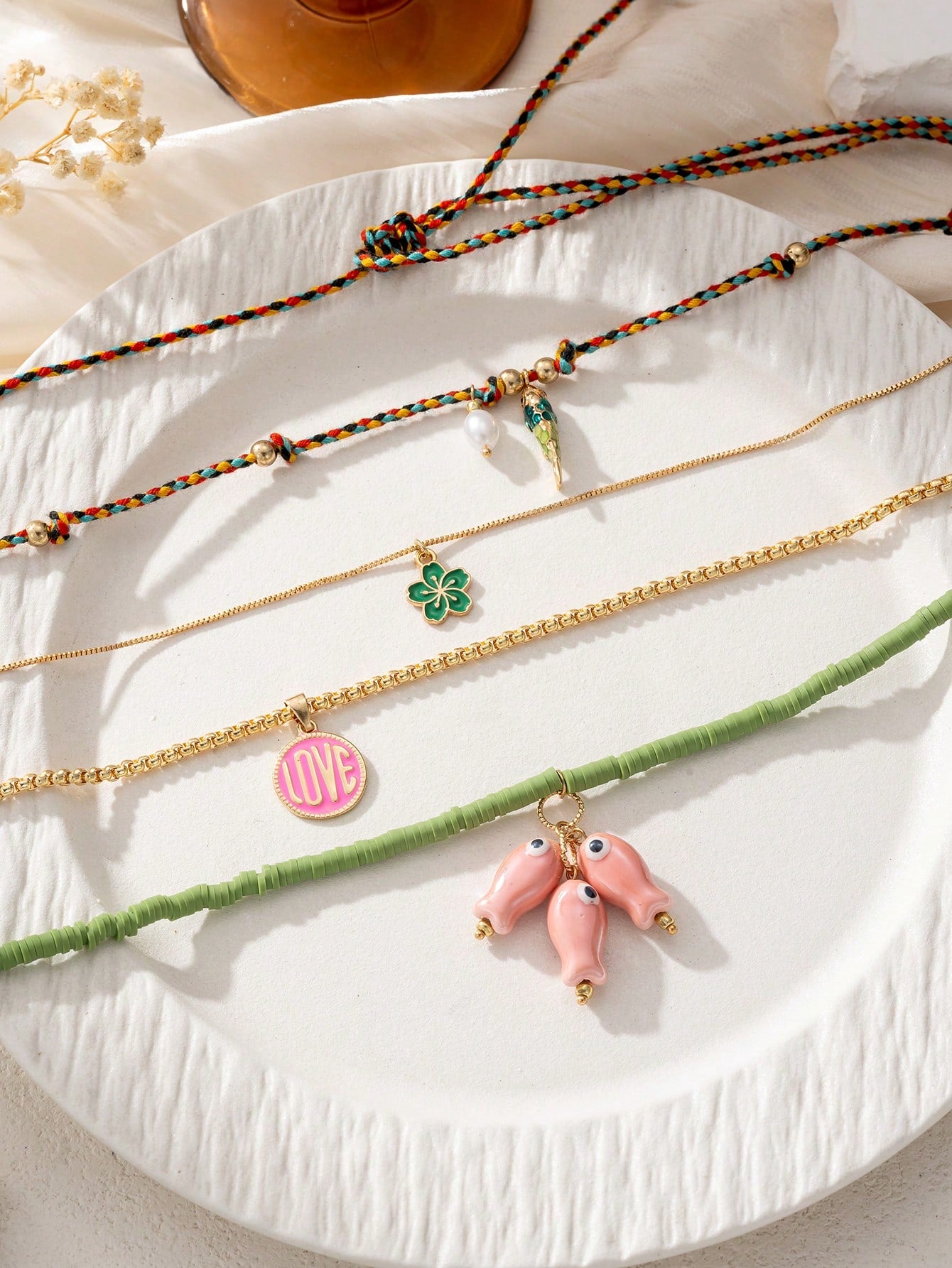 Collection of necklaces with various charms on a textured surface