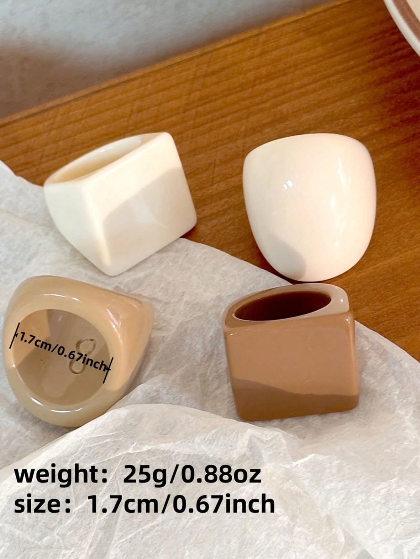 Four ceramic pots of different colors on a wooden surface with text indicating weight and size.