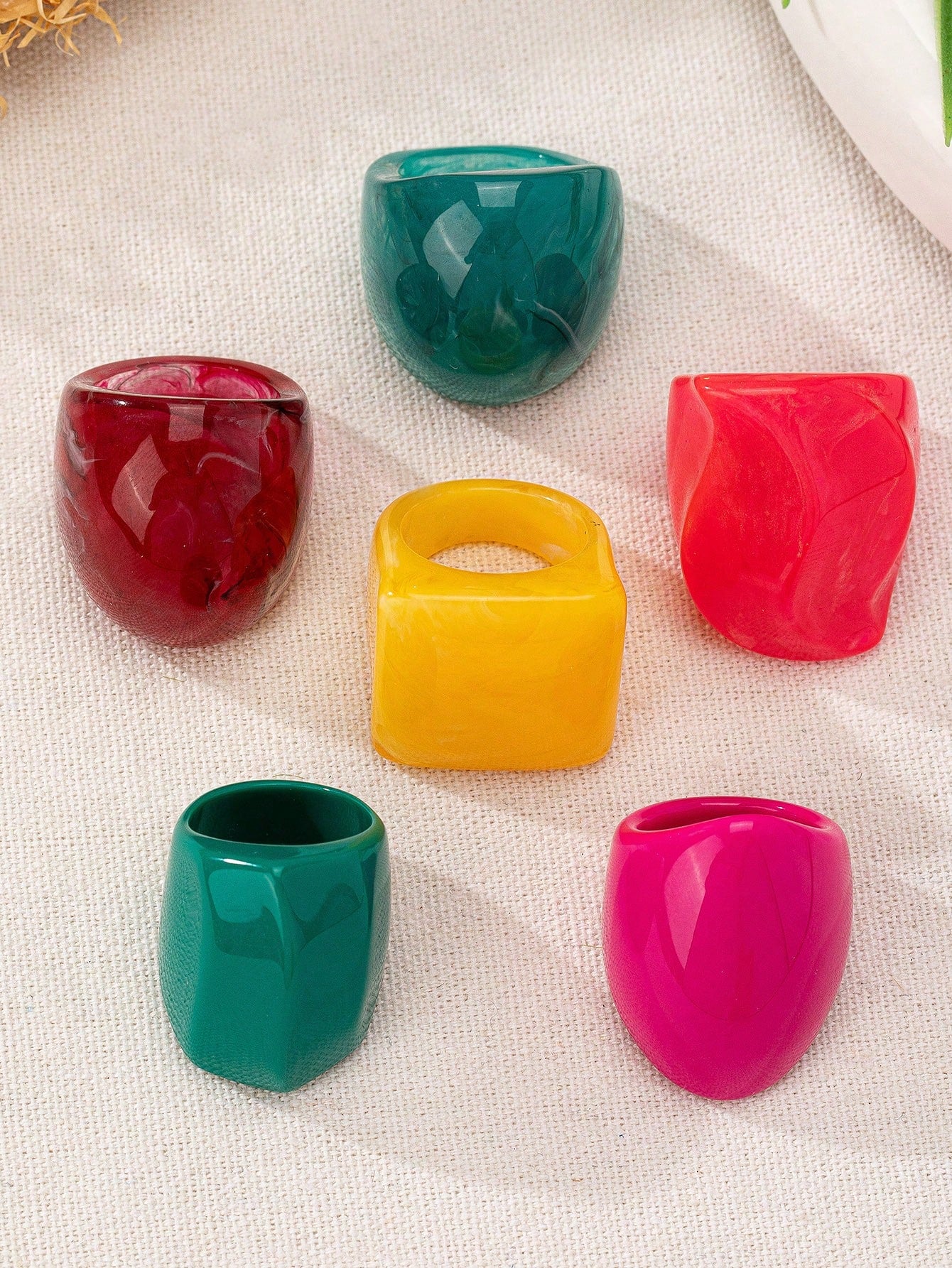 Set of colorful resin rings on a textured fabric background