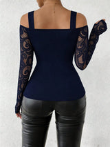 A woman shown from the back wearing a navy blue cold-shoulder top with long lace sleeves and black faux-leather pants, against a light textured wall.