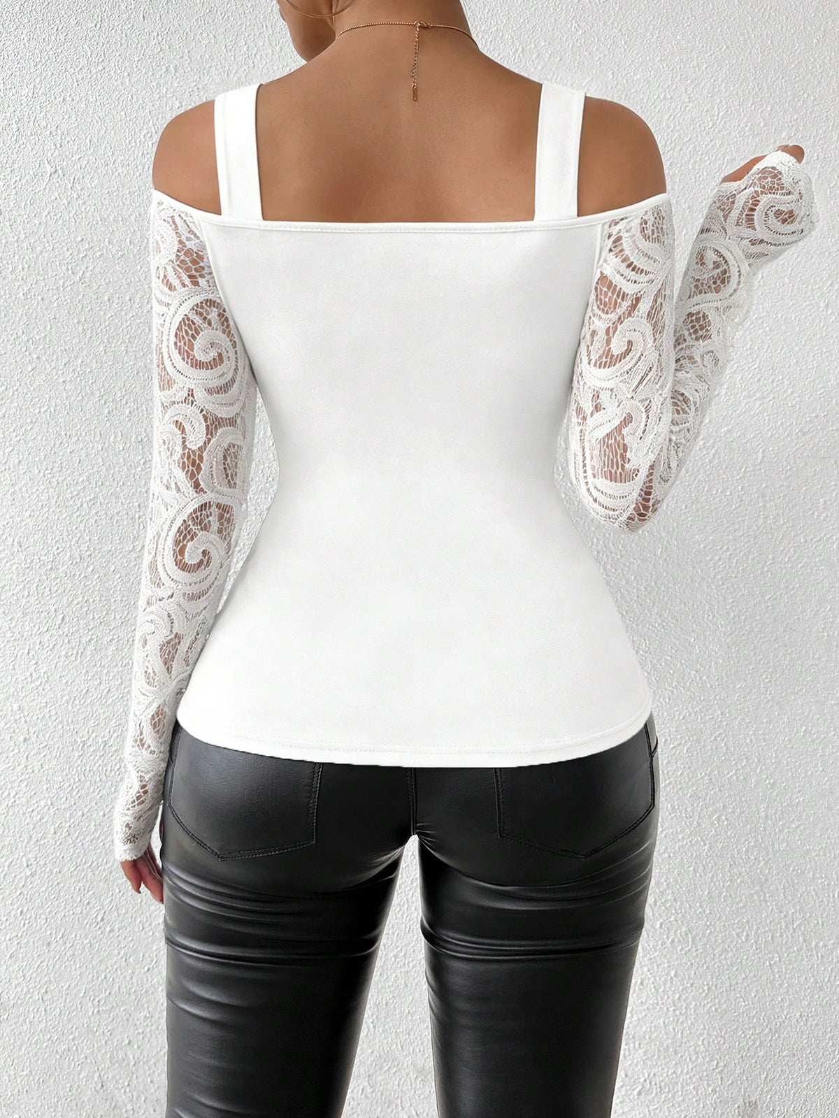 White top with lace sleeves worn by a person against a plain background