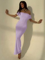 Woman wearing a purple off-shoulder dress against a plain background