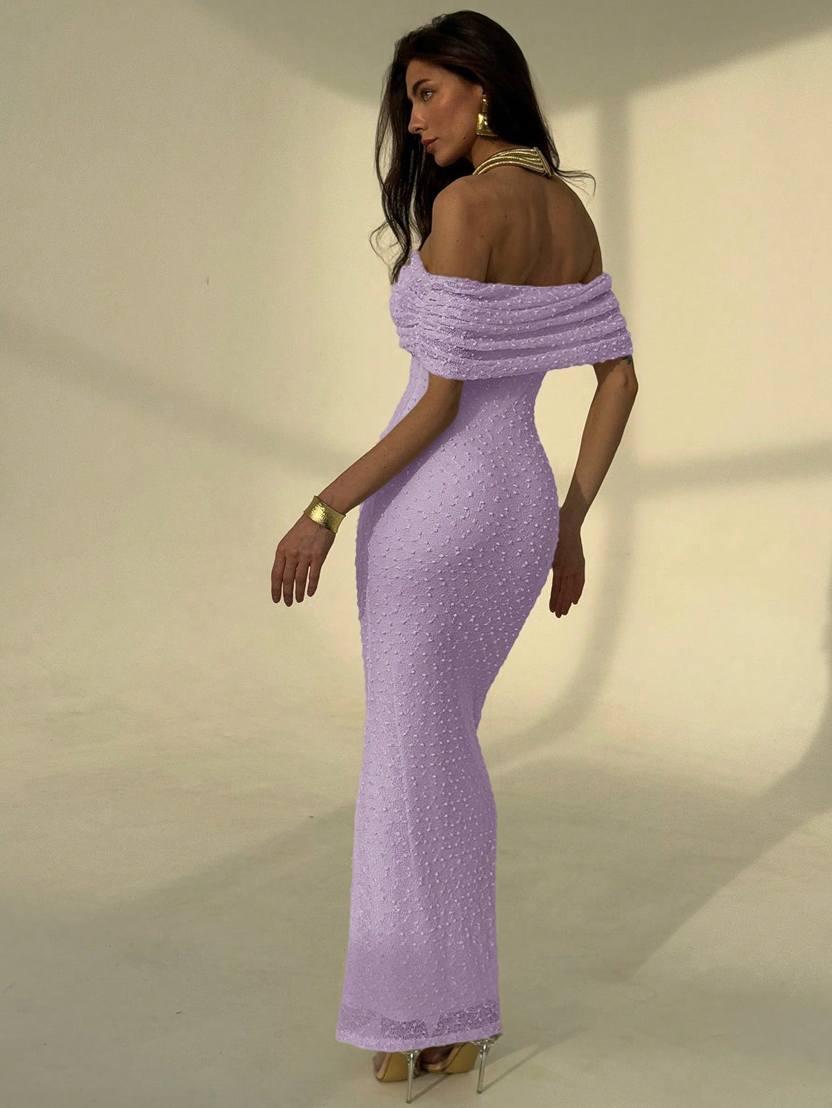 Woman wearing a purple off-shoulder dress against a neutral background