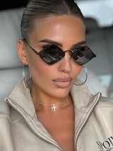 Woman wearing sunglasses and a light-colored jacket with a blurred background