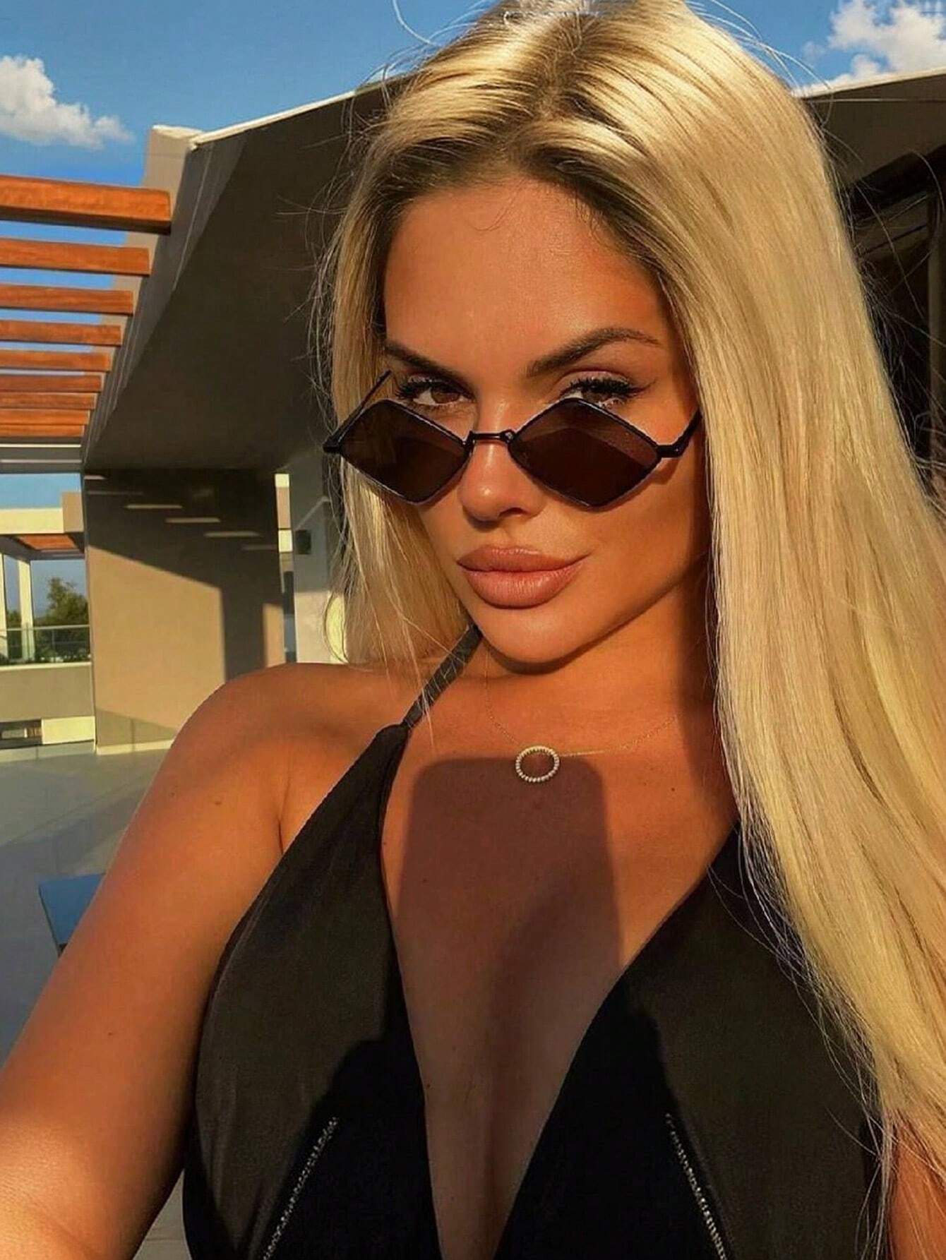 Woman wearing sunglasses and a black outfit with a modern building in the background