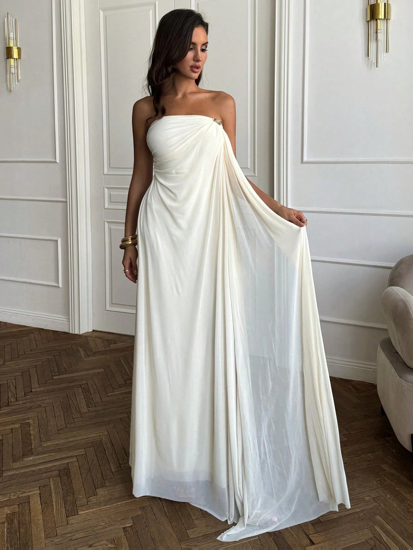 Woman wearing a strapless white gown with a flowing skirt in an elegant room.