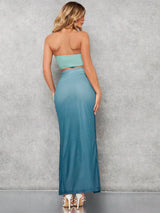 Woman wearing a strapless mint top and blue skirt against a gray background