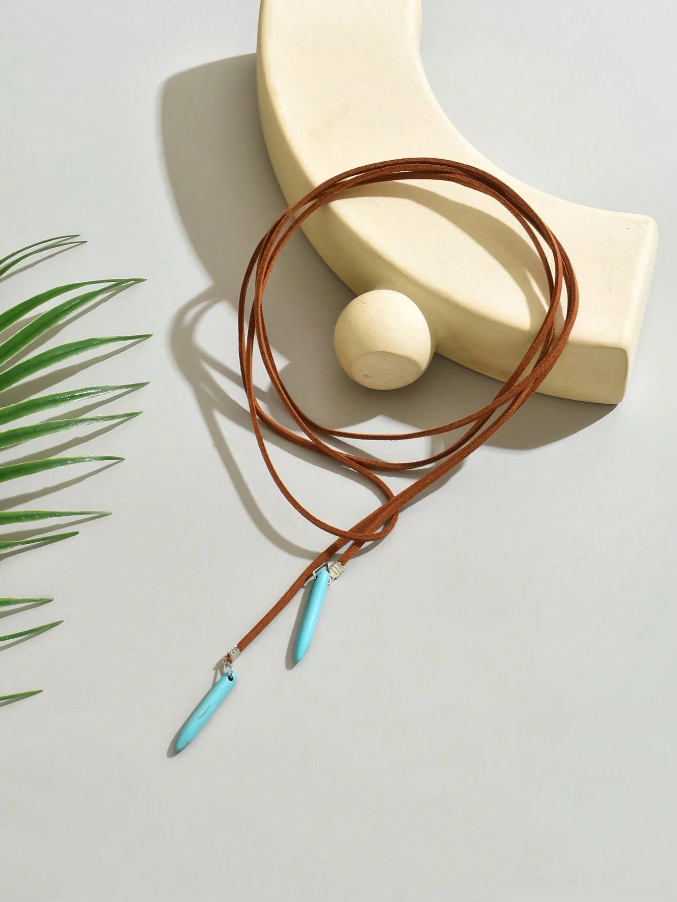 Brown leather necklace with blue pendants on a light gray background