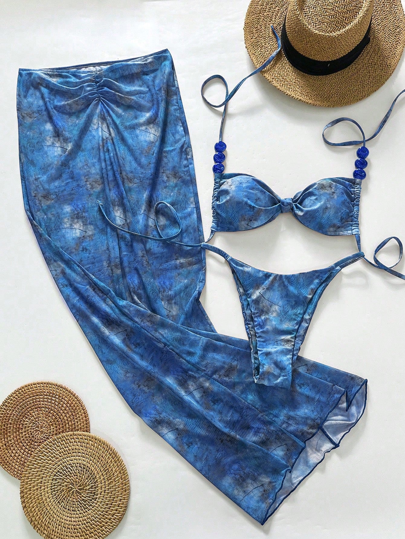 Blue tie-dye swimsuit with a hat and sandals on a white background