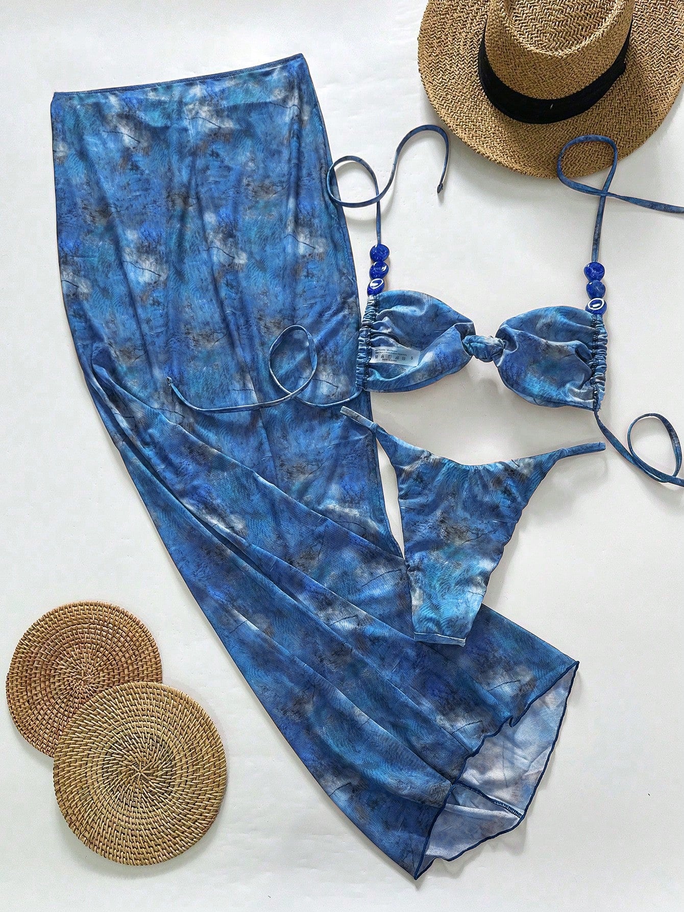 Blue tie-dye swimsuit with a hat and coasters on a white background