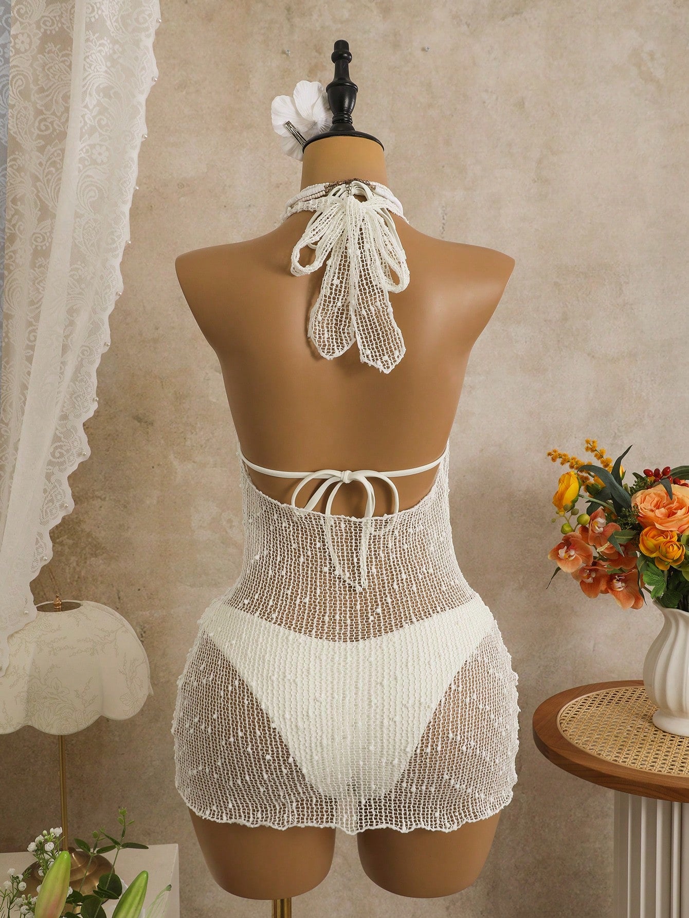 White crochet outfit on a mannequin against a neutral background