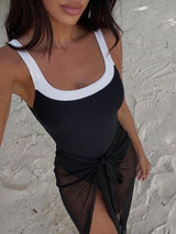 Woman wearing a black and white dress against a textured wall.