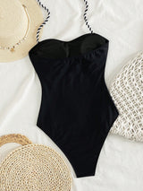 Black swimsuit with straw hat and bags on a white background