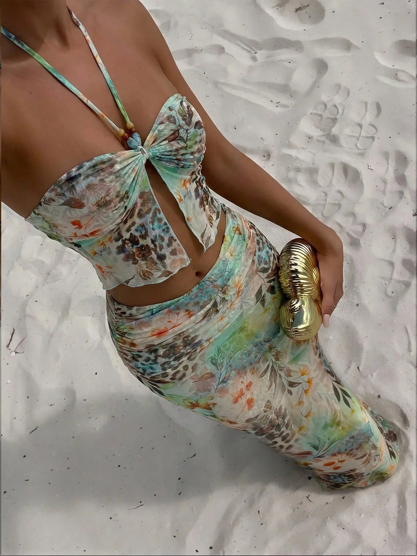Person wearing a colorful floral swimsuit on a sandy beach.