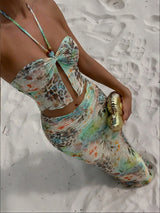 Person wearing a colorful floral swimsuit on a sandy beach.