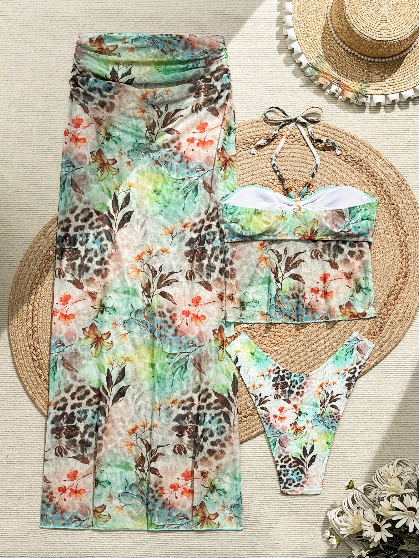 Floral and animal print bikini set with matching pants on a woven mat.
