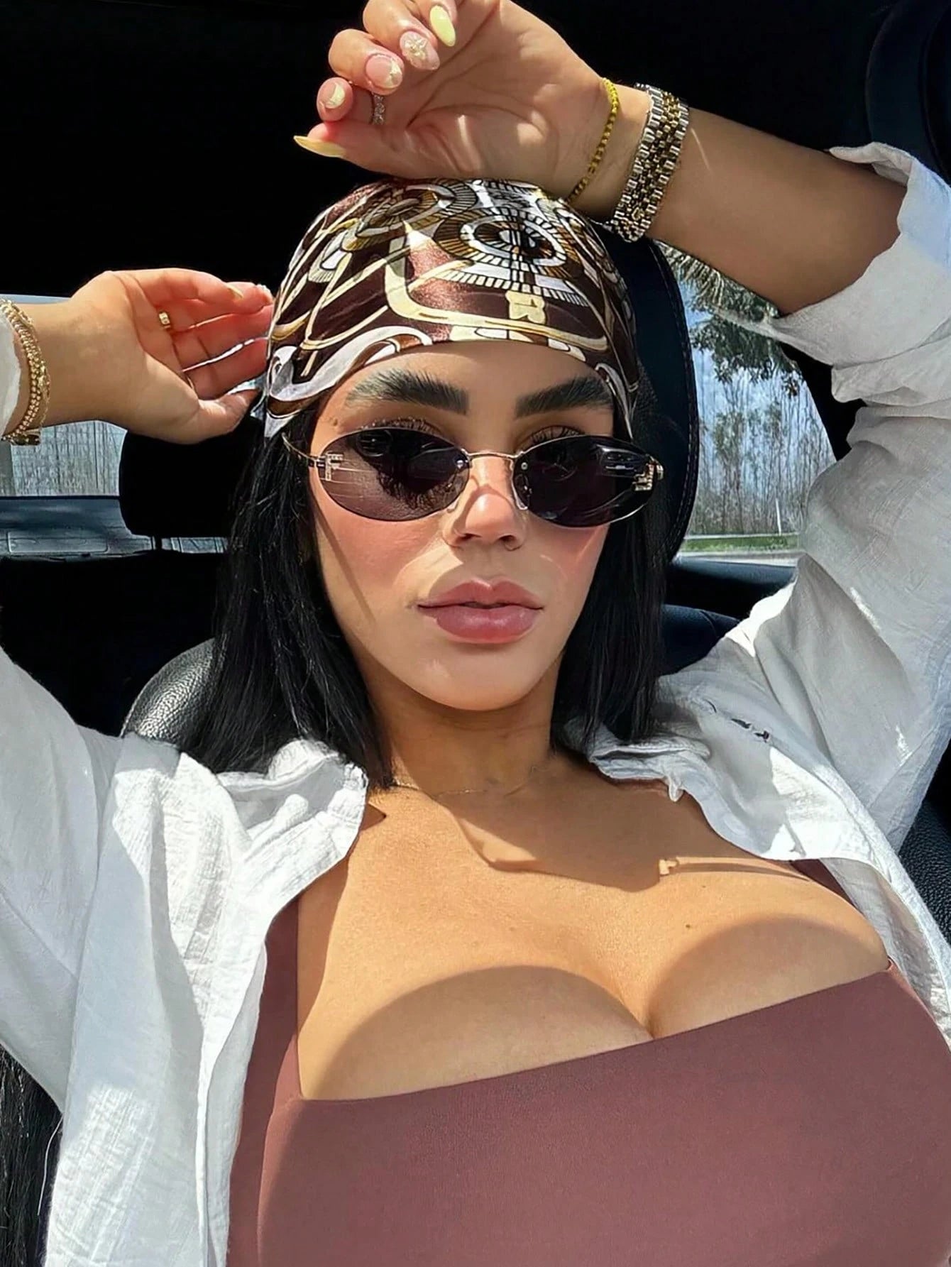 Woman wearing sunglasses and a patterned headscarf in a car