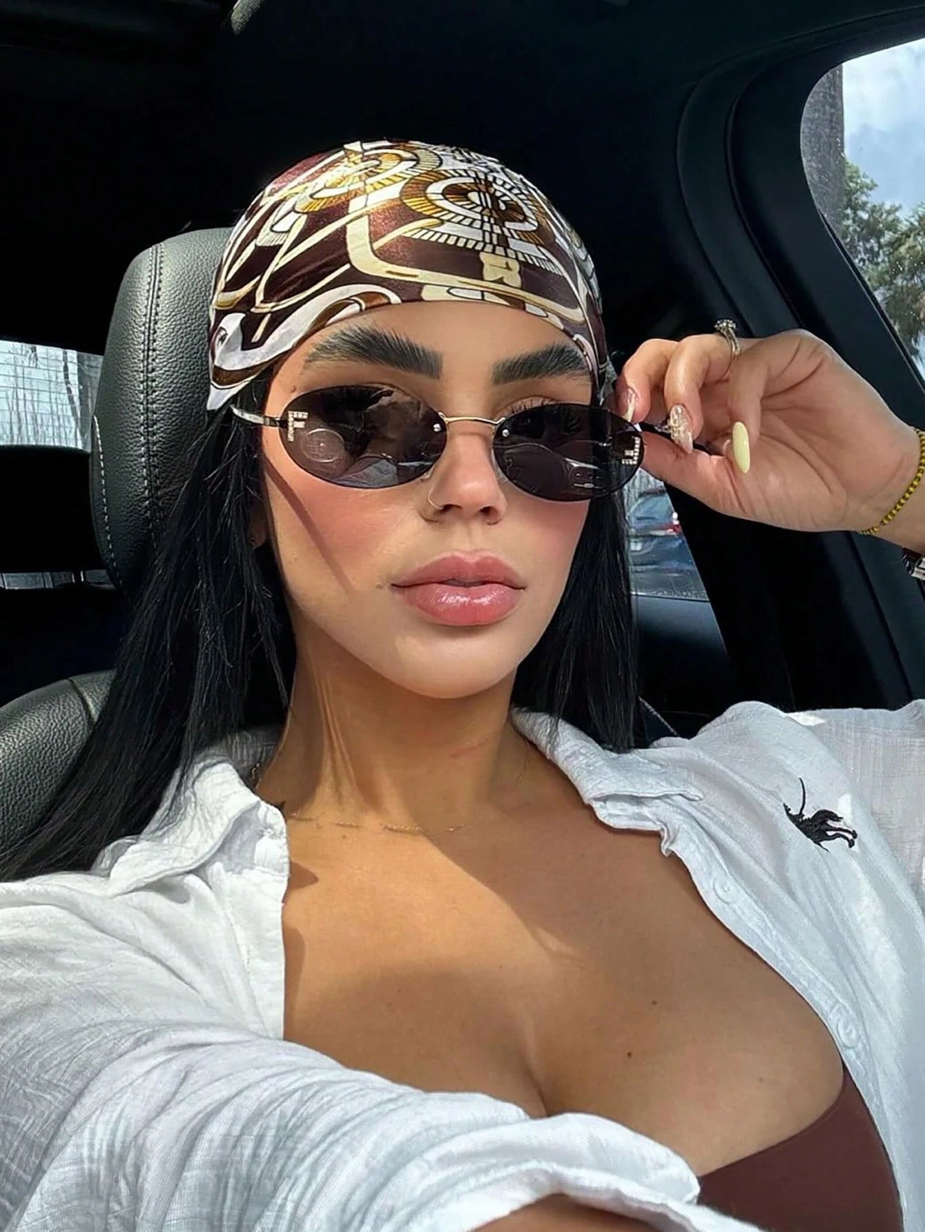 Woman wearing a patterned headscarf and sunglasses inside a car