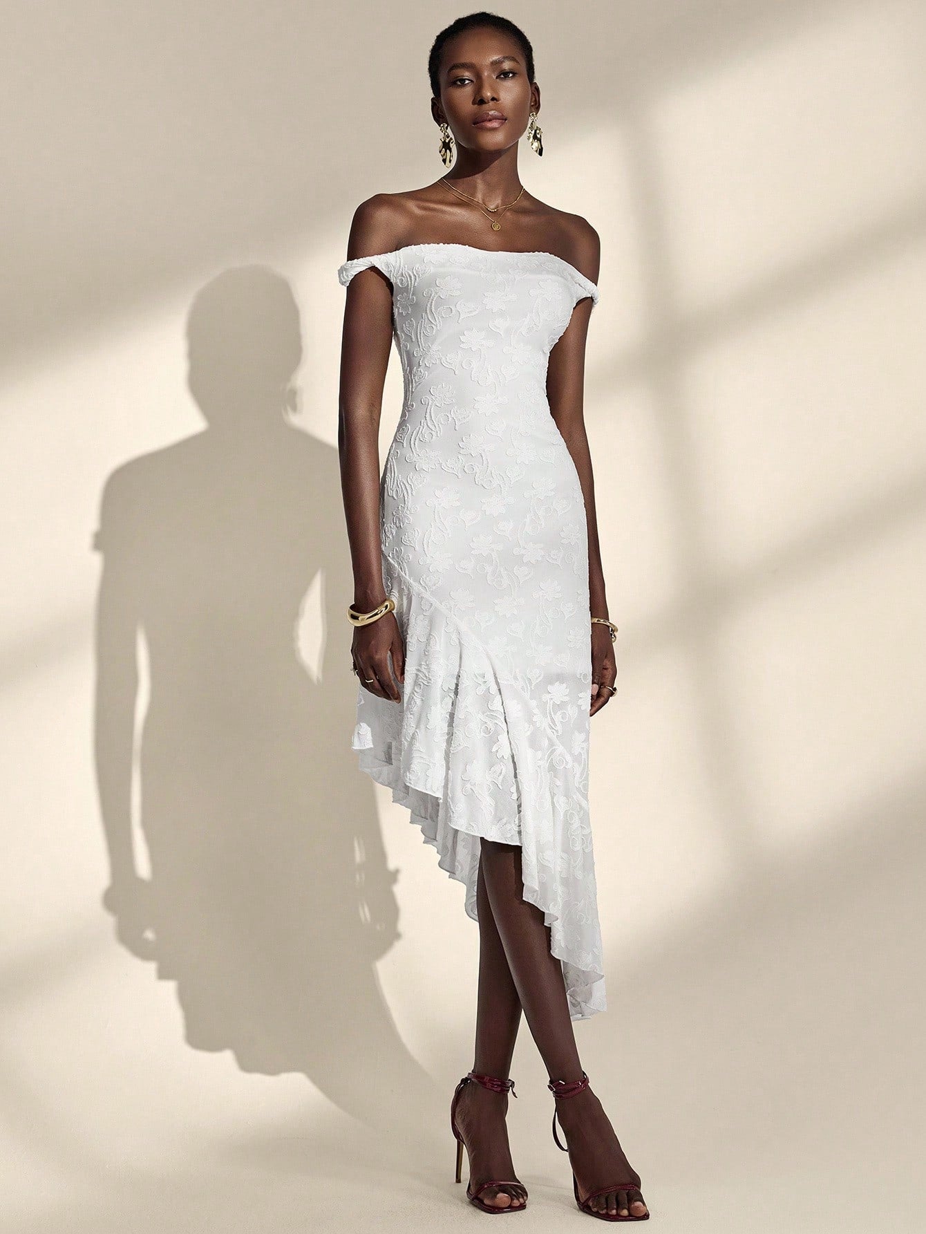 Woman wearing a white off-shoulder dress against a neutral background