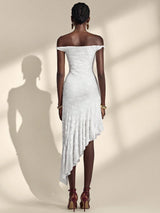 Woman wearing a white off-shoulder dress with a high-low hem on a beige background