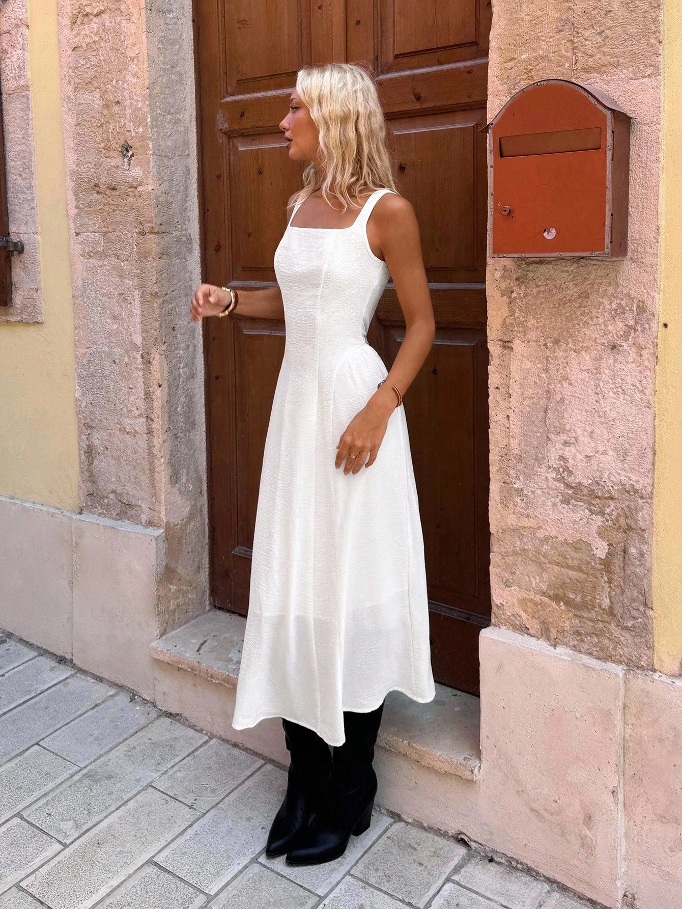 Woman in a white dress standing in front of a building entrance.