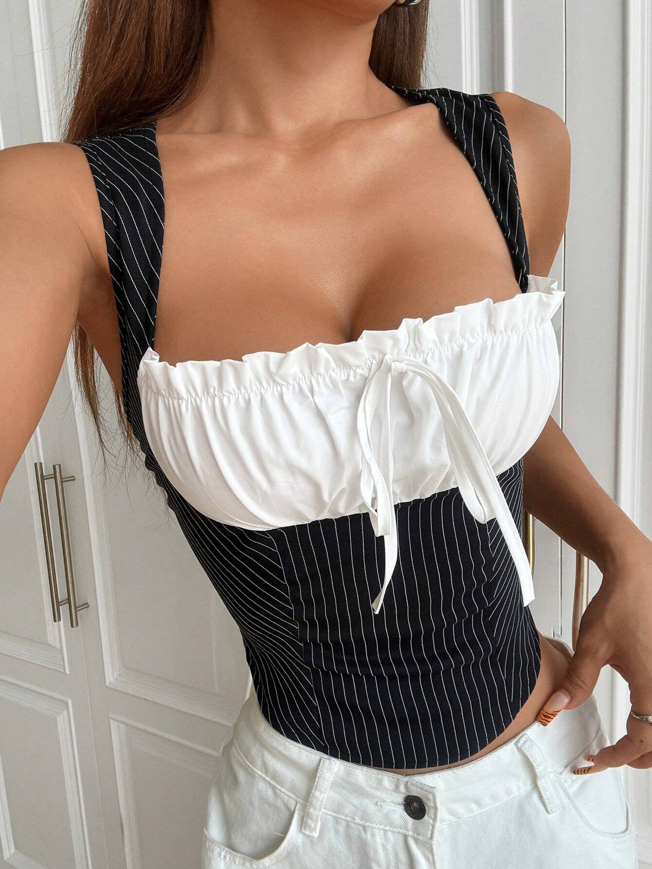 Woman wearing a black and white pinstripe top with a white skirt.