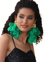 Woman wearing large green floral earrings on a white background
