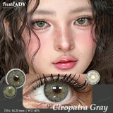 A close-up beauty graphic showing a model's face and an enlarged eye wearing a gray-green contact lens. The image includes inset circular lens views, the text 'FreshLADY', 'Cleopatra Gray', and size/weight details.