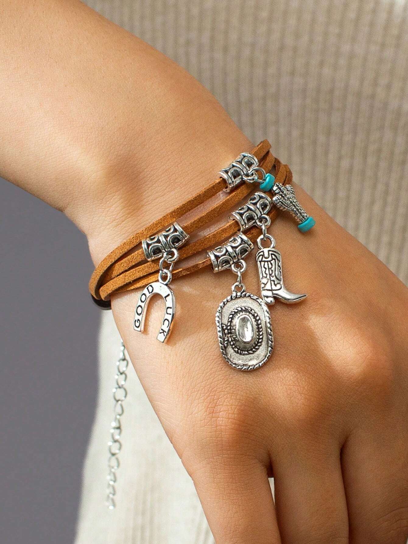 Bracelet with charms on a wrist against a neutral background