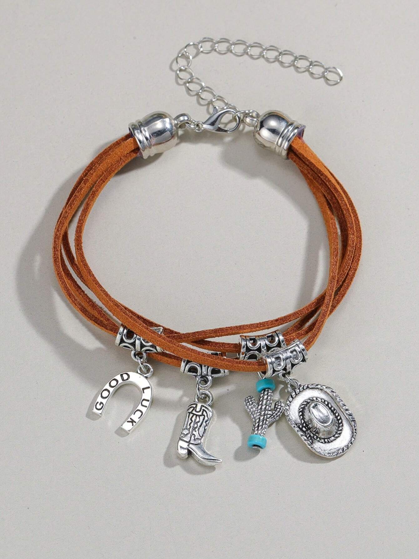 Bracelet with leather straps and various charms on a light gray background