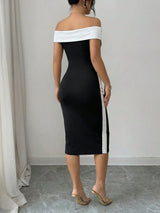 Woman wearing a black and white off-shoulder dress against a plain background