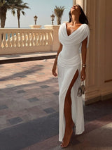 Woman in a white dress standing on a balcony with palm trees in the background